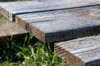 Güneşli bir bahar gününde parktaki eski tahtaların olduğu ahşap bir masanın parçası. Metin veya tasarım için alanı kapat ve kopyala