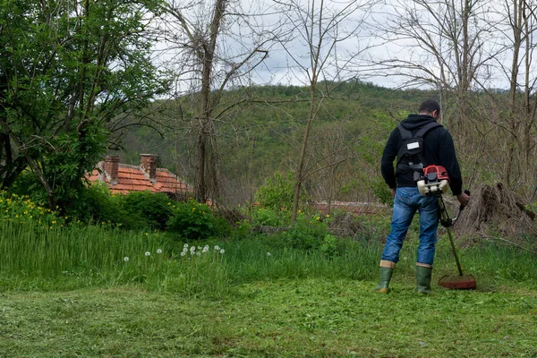 Man Klipper Gräset Med Trimmer Vårdag Jordbrukare Slåtter Gräs Trädgården — Stockfoto