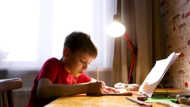 Портрет сконцентрированного кавказского ребенка, делающего домашнее задание за столом дома. Вдумчивый школьник. Образование, учеба, обучение — стоковое видео