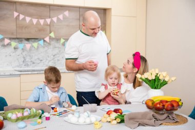 Mutlu Aile Paskalya için hazırlanıyor. Yumurta boyayan sevimli çocuklar. Ev aktivitesi. Birlik ve sevgi kavramı. Anne, baba, oğul, kız. Erkek ve kız kardeş
