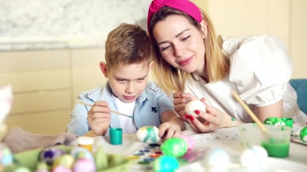 Glückliche Familie bereitet sich auf Ostern vor. Nettes Kind mit Mutter beim Bemalen von Eiern. Heimaktivität. Konzept der Einheit und Liebe. Mutter und Sohn. — Stockvideo