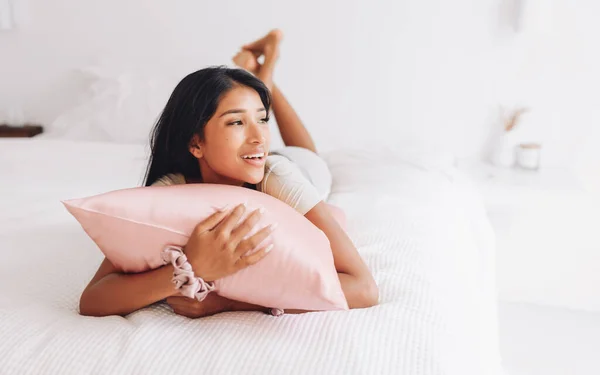 美丽的印尼姑娘躺在一个粉色枕头上 上面有一个丝绸枕套 — 图库照片
