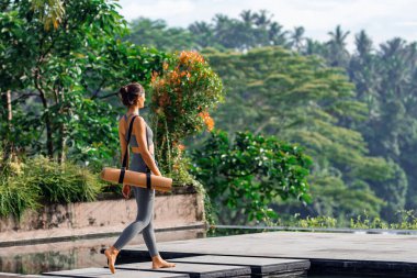 Tropikal tuvaletli yoga minderli kız.