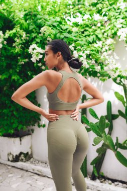 Fitnes spor modelinin Asyalı modeli beyaz duvarın üzerinde moda spor kıyafetleriyle poz veriyor.