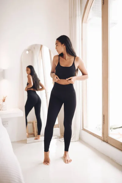 Fitnes spor modelinin Asyalı modeli beyaz duvarın üzerinde moda spor kıyafetleriyle poz veriyor.