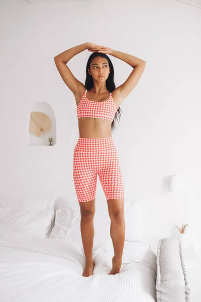 Fitnes spor modelinin Asyalı modeli beyaz duvarın üzerinde moda spor kıyafetleriyle poz veriyor.