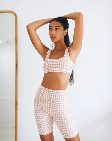 Asian model of fitnes sport appearance in trendy sportswear posing over white wall