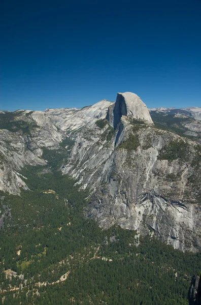 Clear skies let the sun shine down on Half Dome inside of Yosemitie National Park. — Stock Photo, Image