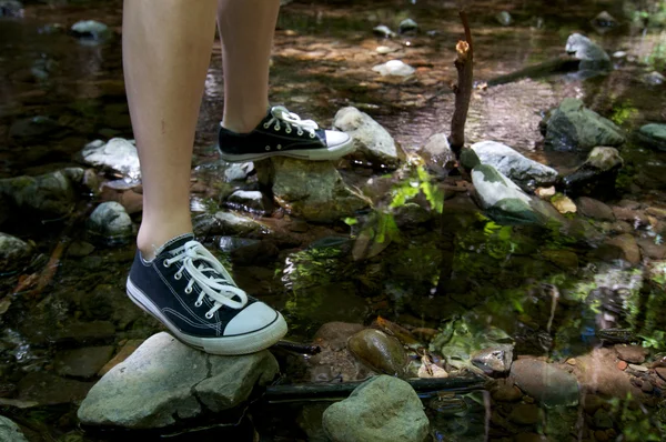 Woman standing on rocks over a creek — Stock Photo, Image