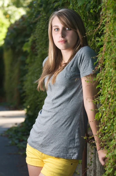 Függőleges tizenéves lány áll közel, a fenyőfák árnyékában szőlő — Stock Fotó
