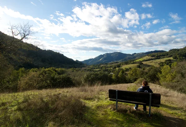 Woman hiker rests at a bench with scenic view — Stock Photo, Image