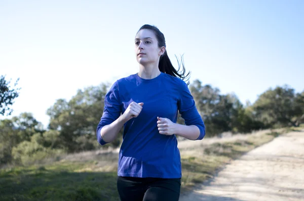 Centered close up of woman jogging outside, facing left — Stock Photo, Image