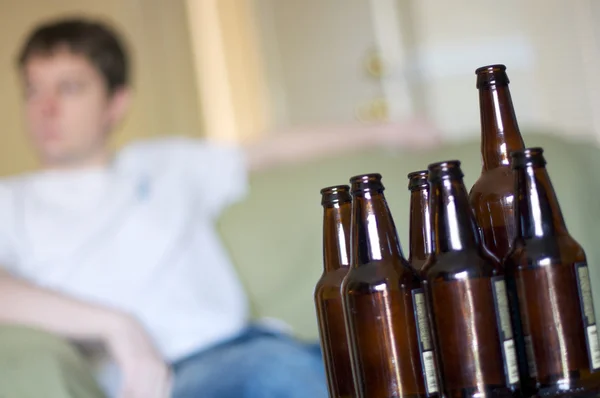 Hombre mirando a la izquierda con un grupo de botellas de cerveza vacías, en ángulo Imagen de stock