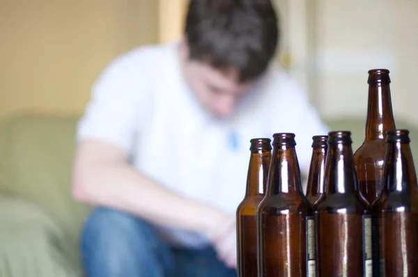 El hombre parece deprimido con botellas de cerveza vacías Imágenes de stock libres de derechos