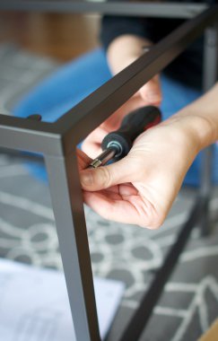 Vertical close up of hands screwing together furniture pieces clipart