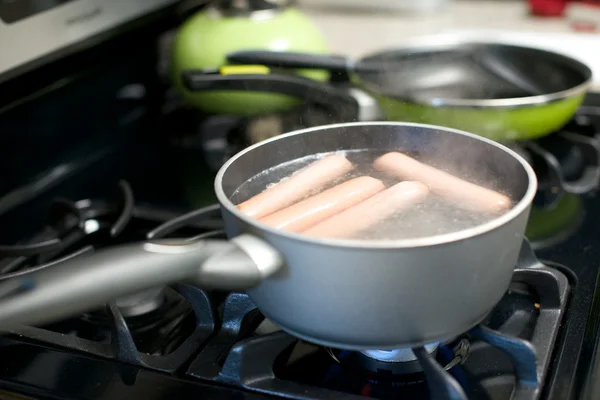 Hot dogs boil on a gas stove — Stock Photo, Image