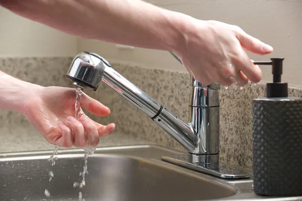 Hands reach for soap at the kitchen sink — Stock Photo, Image