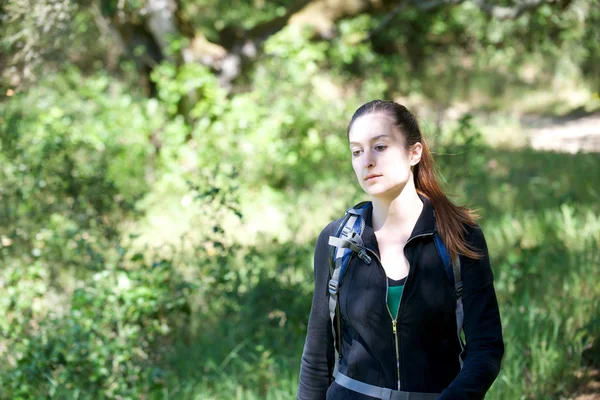 Junge Frau wandert durch schattigen Wald — Stockfoto