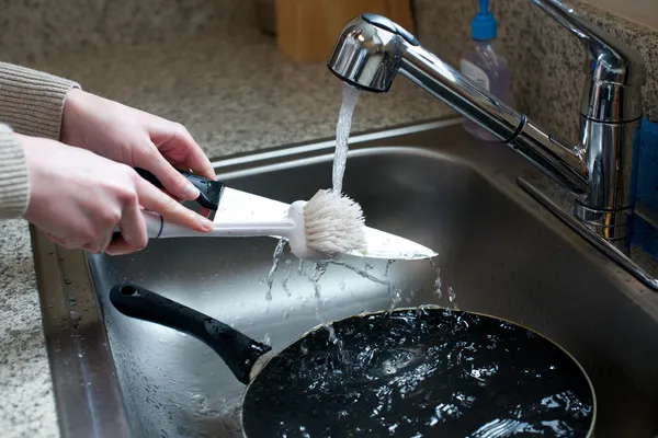 Close up of hands scrubbing knife in sink — Stock Photo, Image