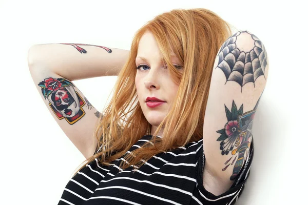 Tête rouge blonde fraise appuyée contre un mur avec des bras de tatouage — Photo