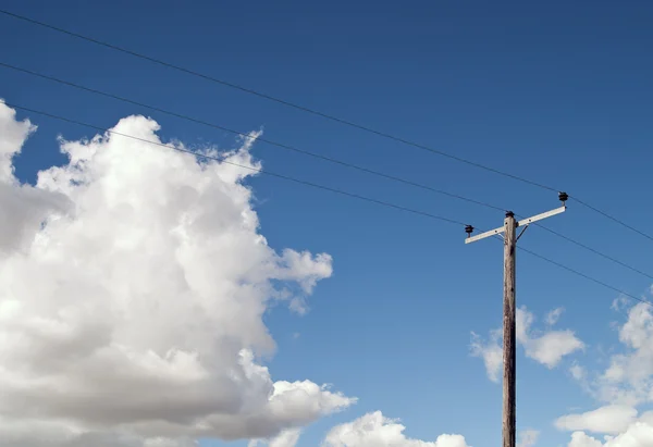 青空とふわふわ雲の上に電気ポール — ストック写真