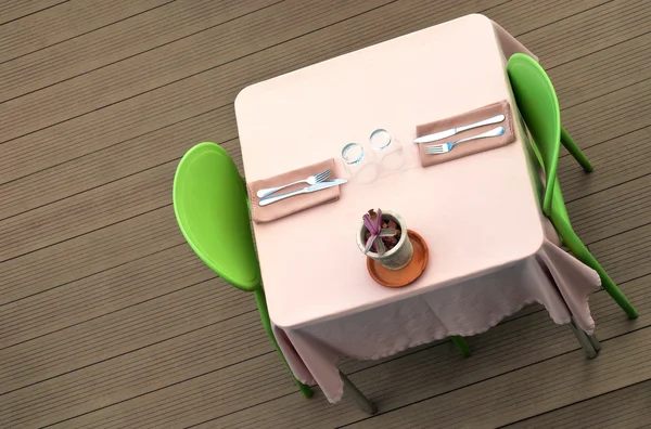 Eettafel met roze tafellaken en groene stoelen en plant Stockfoto
