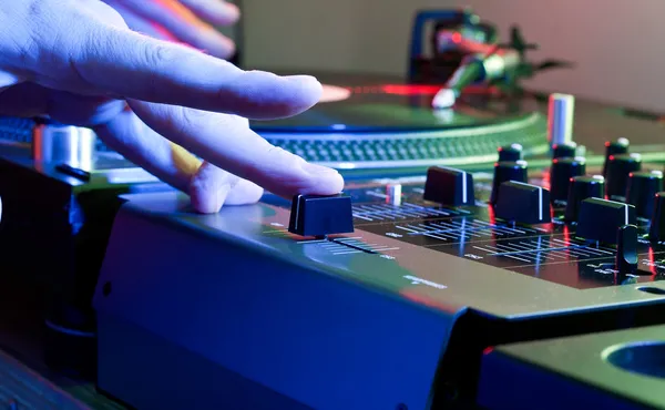 DJ Hand zwickt den Crossfader eines Musikmischpults Stockbild