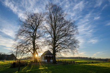 Gün doğumunda ağaçların altındaki küçük şapelin panoramik görüntüsü, Bergisch Gladbach, Almanya
