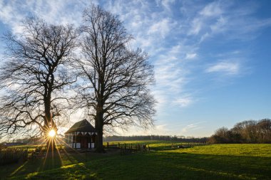 Gün doğumunda ağaçların altındaki küçük şapelin panoramik görüntüsü, Bergisch Gladbach, Almanya