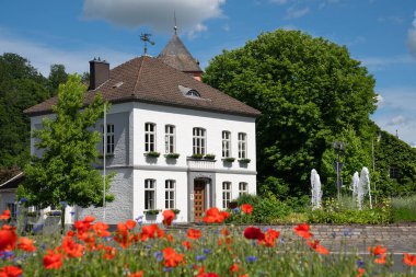 ODENTHAL, ALMANY - 25 Mayıs 2022: Odenthal köyünün Townhall 'ı, 25 Mayıs 2022' de Bergisches Land, Almanya 'da gelincik tarlası ile birlikte