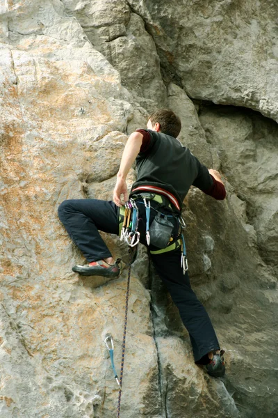 Joven escalando en una pared de piedra caliza con amplio valle en el fondo — Foto de Stock