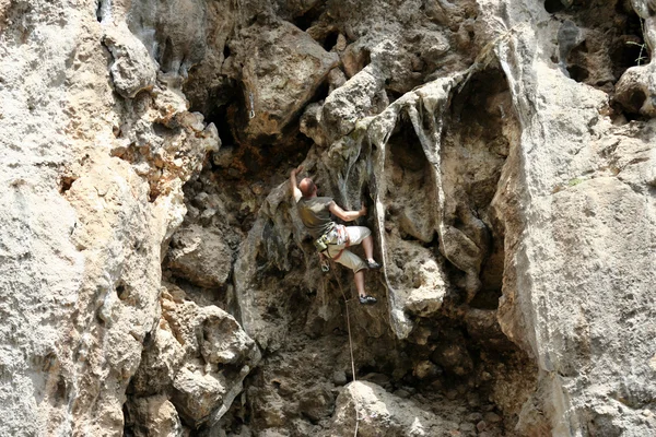 Joven escalando en una pared de piedra caliza con amplio valle en el fondo —  Fotos de Stock