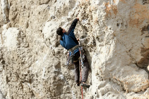 Joven escalando en una pared de piedra caliza con amplio valle en el fondo —  Fotos de Stock