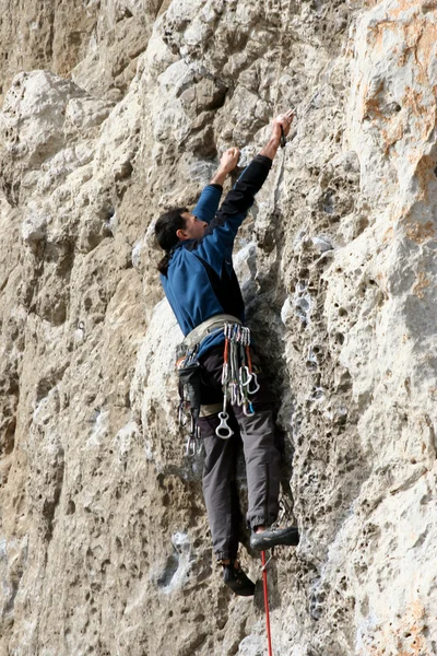 Joven escalando en una pared de piedra caliza con amplio valle en el fondo —  Fotos de Stock