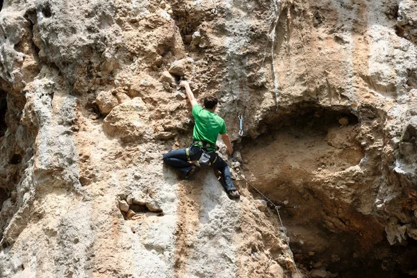 Joven escalando en una pared de piedra caliza con amplio valle en el fondo — Foto de Stock