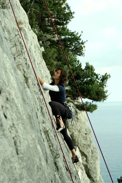 Giovane arrampicata su una parete calcarea con ampia valle sullo sfondo — Foto Stock