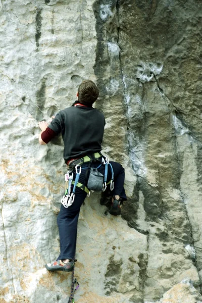 Joven escalando en una pared de piedra caliza con amplio valle en el fondo —  Fotos de Stock