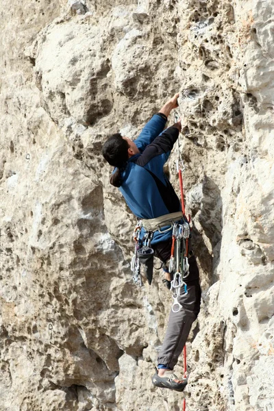 Jovem escalando em uma parede de pedra calcária com amplo vale no fundo — Fotografia de Stock