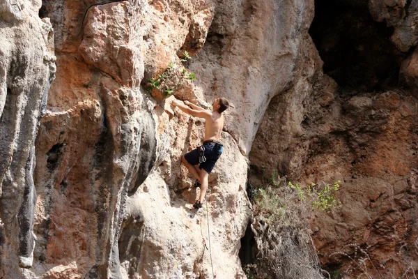 Joven escalando en una pared de piedra caliza con amplio valle en el fondo —  Fotos de Stock