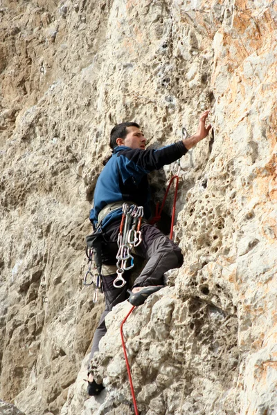 Joven escalando en una pared de piedra caliza con amplio valle en el fondo —  Fotos de Stock