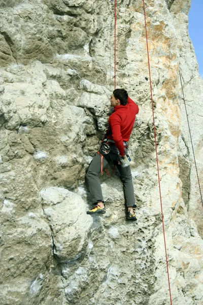 Joven escalando en una pared de piedra caliza con amplio valle en el fondo —  Fotos de Stock