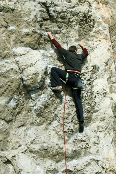 Young man climbing on a limestone wall with wide valley on the background — Stock Photo, Image