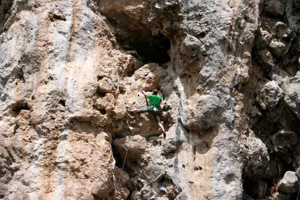 Genç adam arka planında geniş bir vadiyle kireçtaşı bir duvara tırmanıyor. — Stok fotoğraf