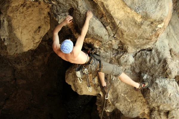 Jovem escalando em uma parede de pedra calcária com amplo vale no fundo — Fotografia de Stock