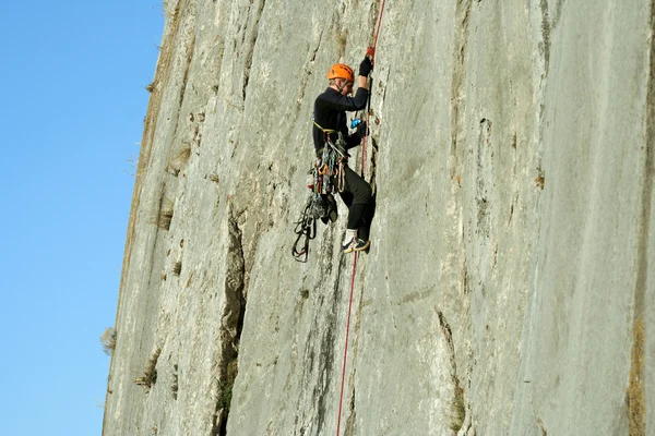 Joven escalando en una pared de piedra caliza con amplio valle en el fondo — Foto de Stock