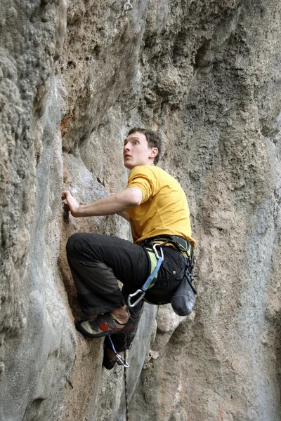 Joven escalando en una pared de piedra caliza con amplio valle en el fondo — Foto de Stock