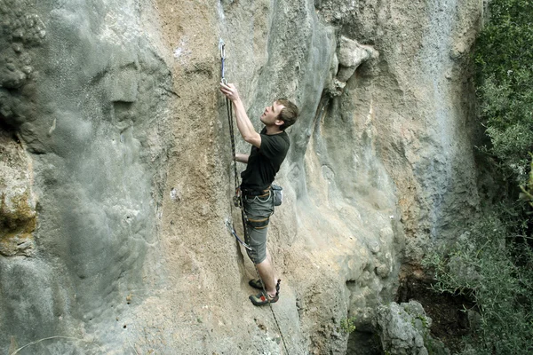 Giovane arrampicata su una parete calcarea con ampia valle sullo sfondo — Foto Stock