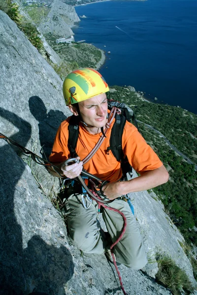 Joven escalando en una pared de piedra caliza con amplio valle en el fondo — Foto de Stock