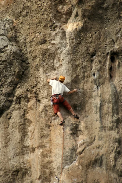 Jovem escalando em uma parede de pedra calcária com amplo vale no fundo — Fotografia de Stock