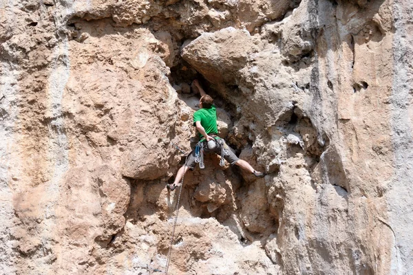 Young man climbing on a limestone wall with wide valley on the background — Stock Photo, Image